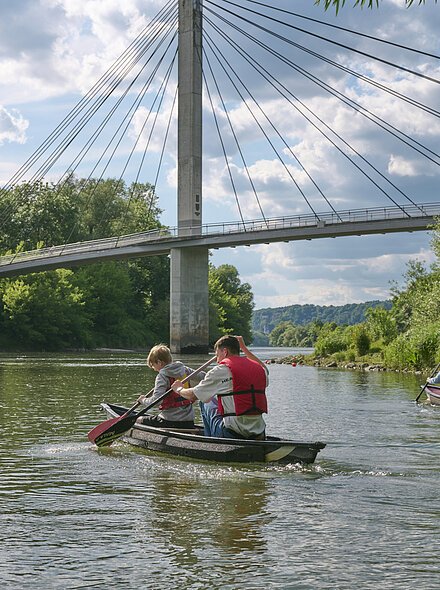 Familie beim Kanufahren mit Blick auf die Fußgängerbrücke